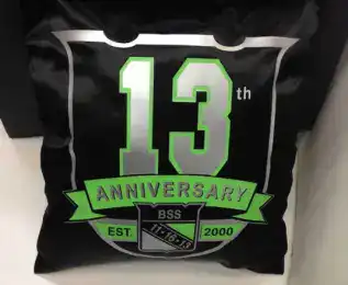 A black pillow displays "13th ANNIVERSARY BSS EST. 2000," ideal for corporate events in New York.