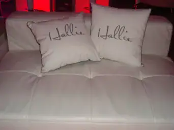 Two white pillows reading "Hallie" rest on a seat, ideal decor for a stylish New York event venue.