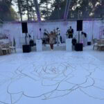 A woman stands on a white dance floor at a sweet sixteen in New York & Long Island beneath a clear tent.