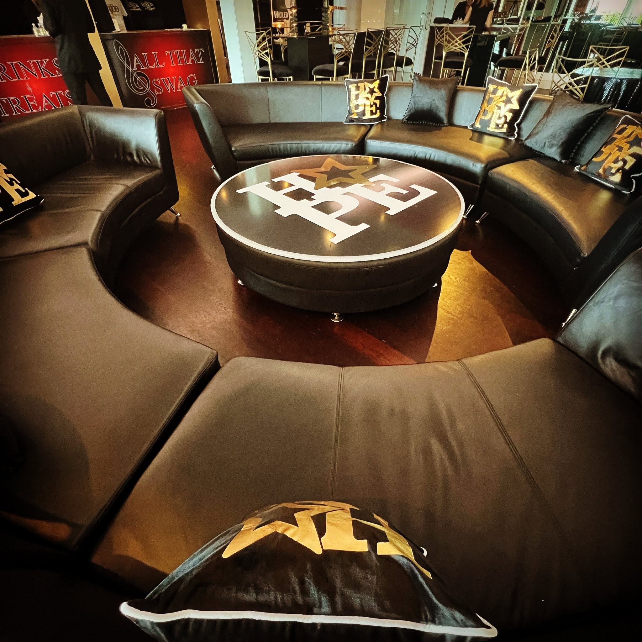 Curved black leather couches and EFE decor set a chic event venue with a New York lounge vibe.
