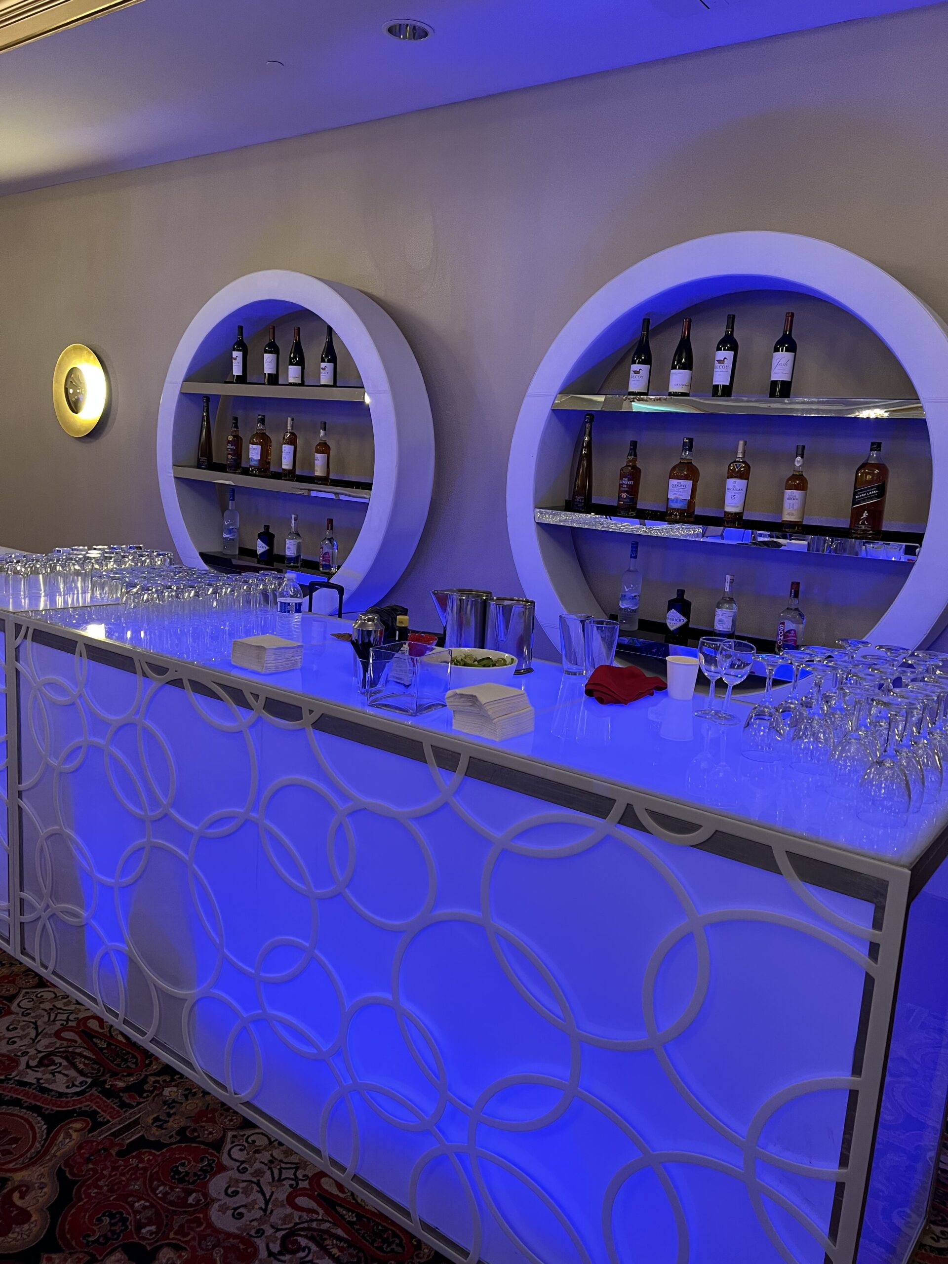 A modern bar with blue lighting and circular shelves, ideal as an event venue in New York or Long Island.