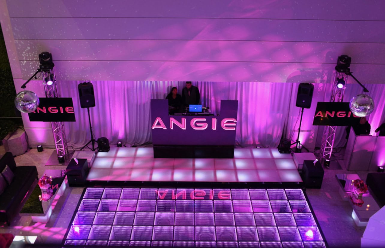A DJ booth labeled "ANGIE" glows with purple lighting at a sweet sixteen in New York, viewed from above.