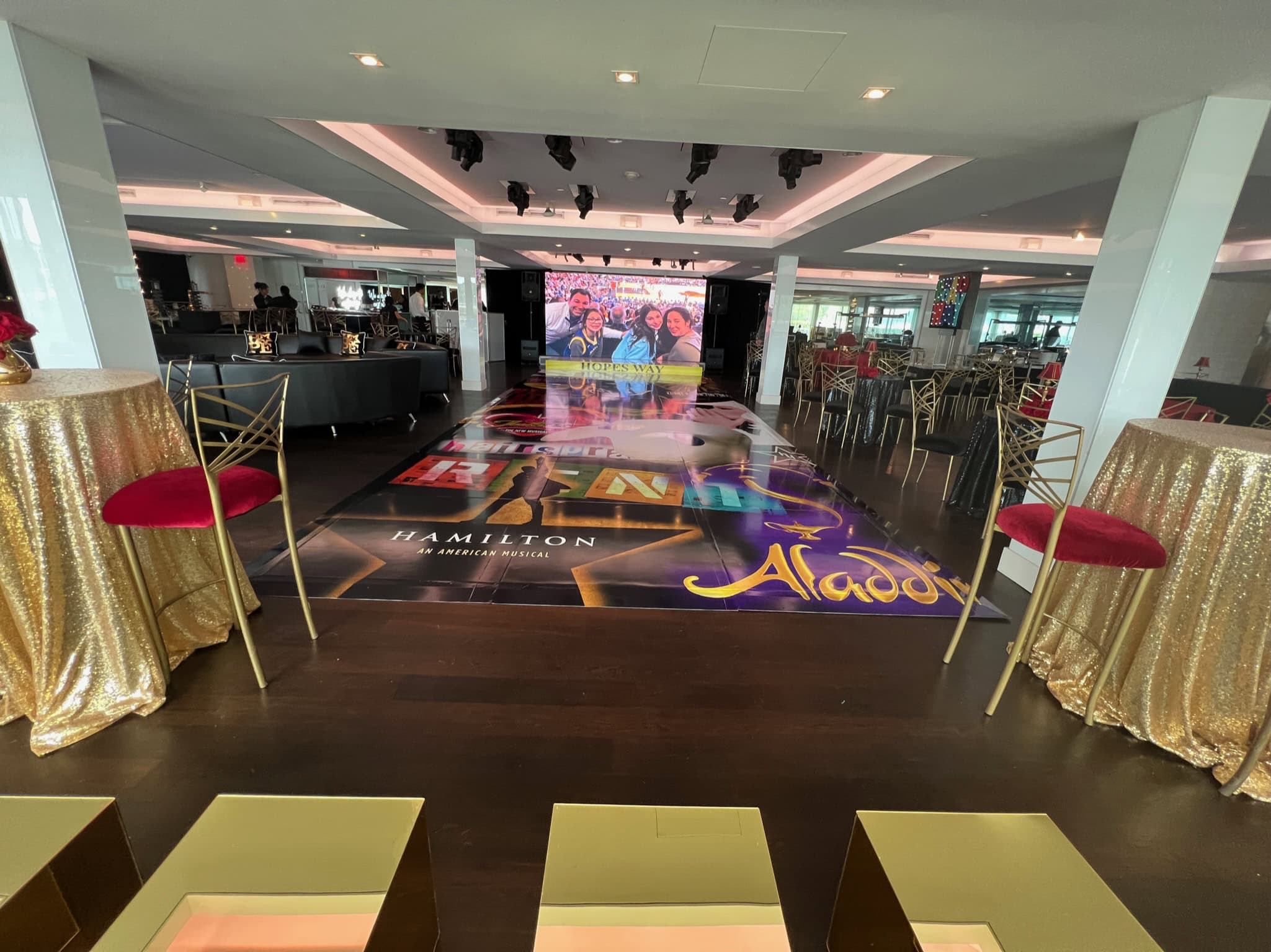 A decorated event venue in New York & Long Island shows a dance floor, music posters, and group photo area.
